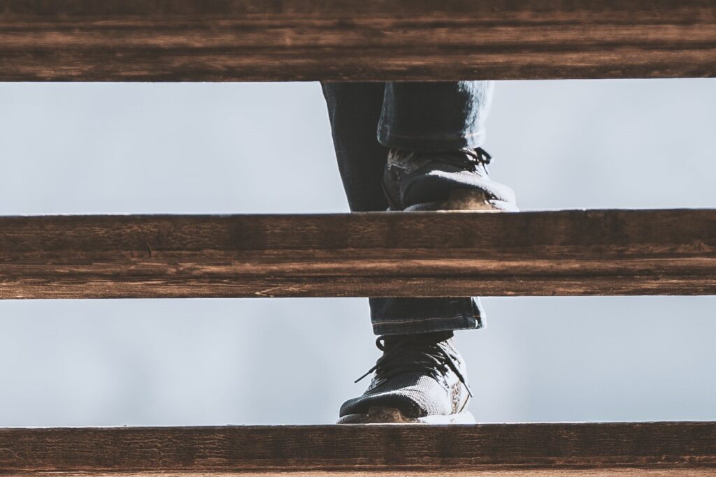 Offene Treppe, durch deren Stufen man eine Person hochsteigen sieht.